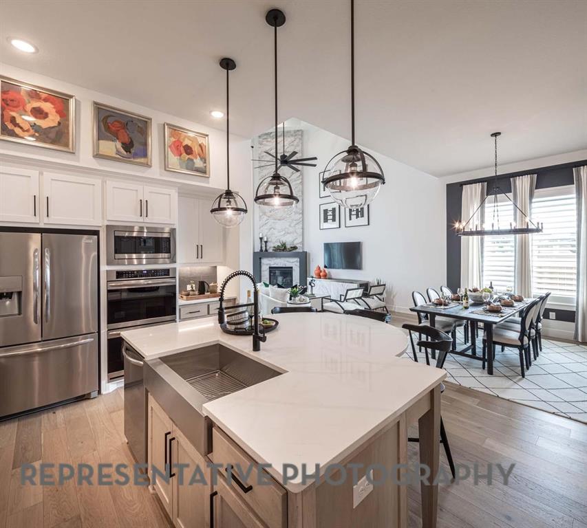 930 Heatherbrook Drive Prosper, TX 75078 - Photo 5 of 37 a kitchen with stainless steel appliances granite countertop a stove a refrigerator a kitchen island a dining table and chairs with wooden floor