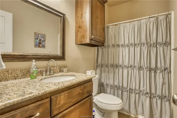 a bathroom with a granite countertop sink a toilet and a mirror