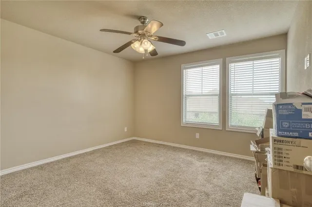 an empty room with windows and fan