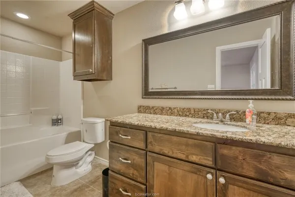 a bathroom with a granite countertop toilet sink and mirror