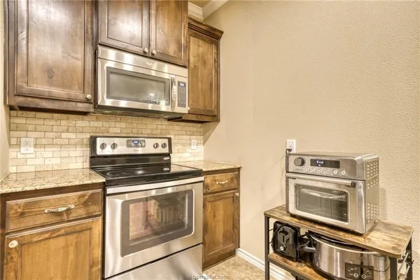 a kitchen with granite countertop a stove top oven microwave and cabinets
