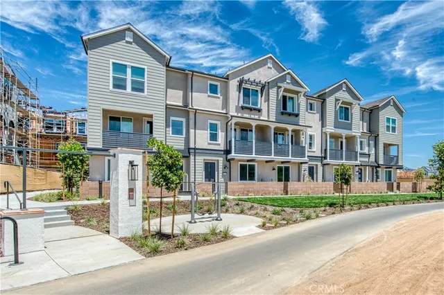 a view of balcony with a couple of cars parked on road in front of house