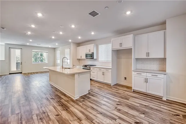 a large kitchen with a center island wooden floor stainless steel appliances and cabinets