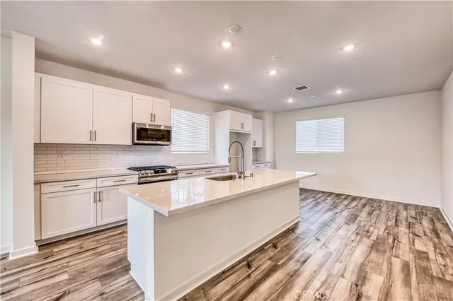 a large kitchen with stainless steel appliances granite countertop a stove a sink and a refrigerator