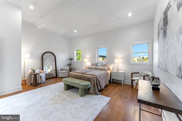 a bedroom with bed and a dresser with wooden floor