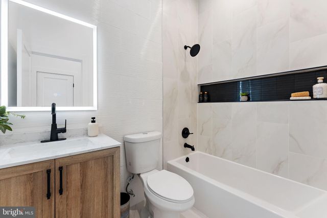 a bathroom with a granite countertop sink a toilet and bathtub