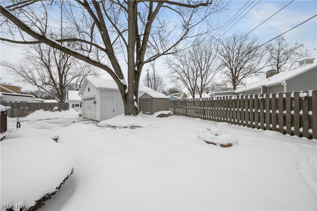 965 Gulf Road Elyria, OH 44035 - Photo 37 of 37 Yard layered in snow featuring a fenced backyard, shed, garage, fire pit area