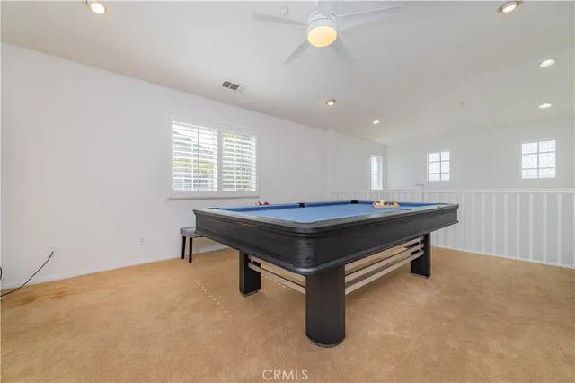 a room with pool table windows and a ceiling fan