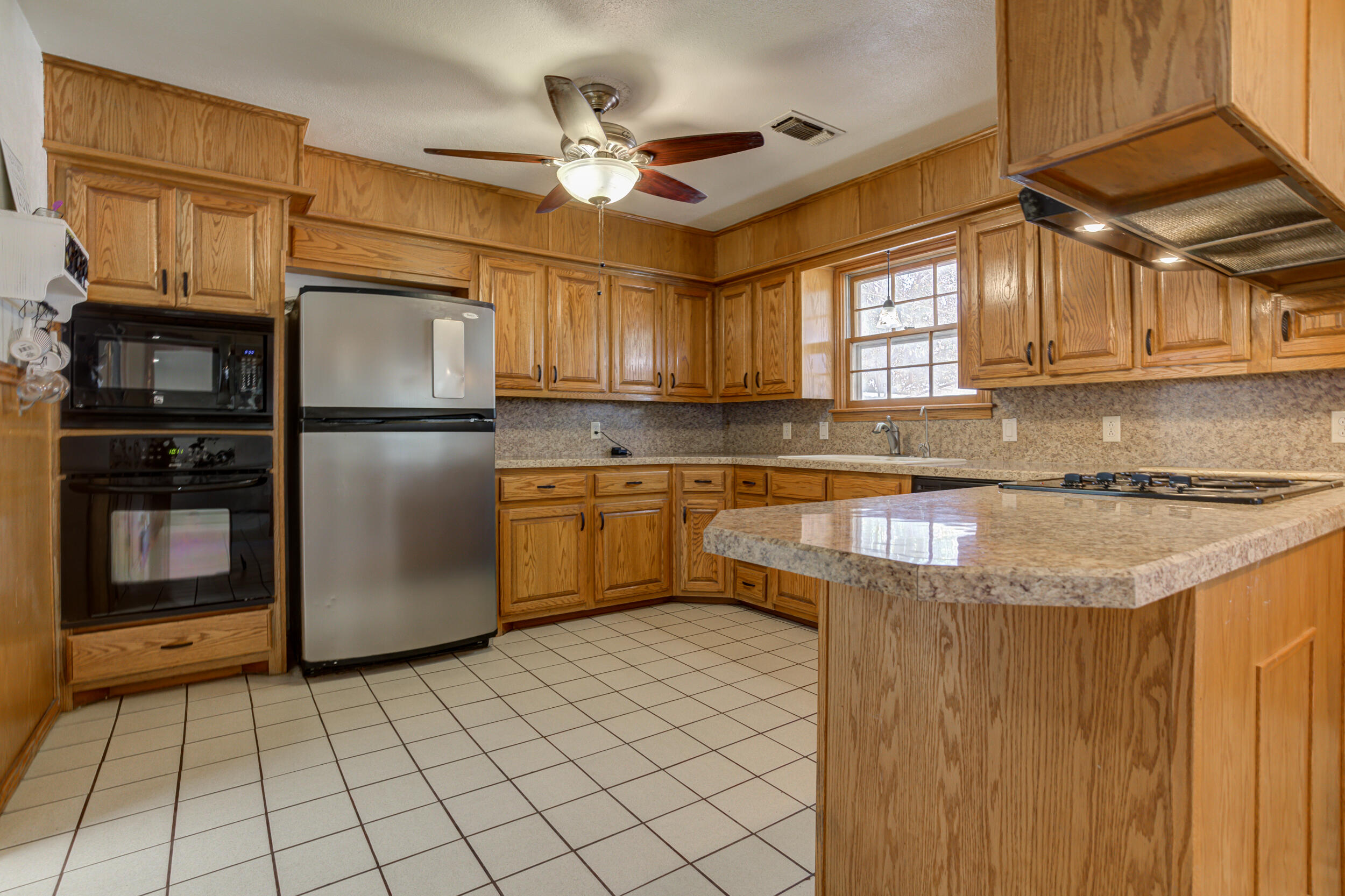 2120 53rd Street Lubbock, TX 79412 - Photo 11 of 32 a kitchen with kitchen island granite countertop a sink appliances cabinets and a counter top space