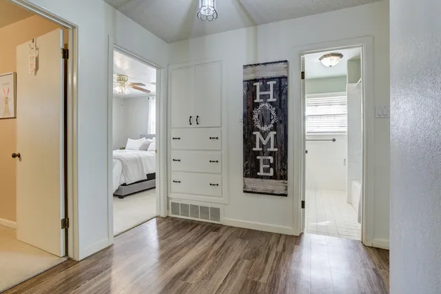 an empty room with wooden floor closet and windows
