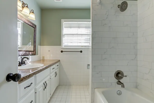 a bathroom with a double vanity sink a mirror and a bathtub