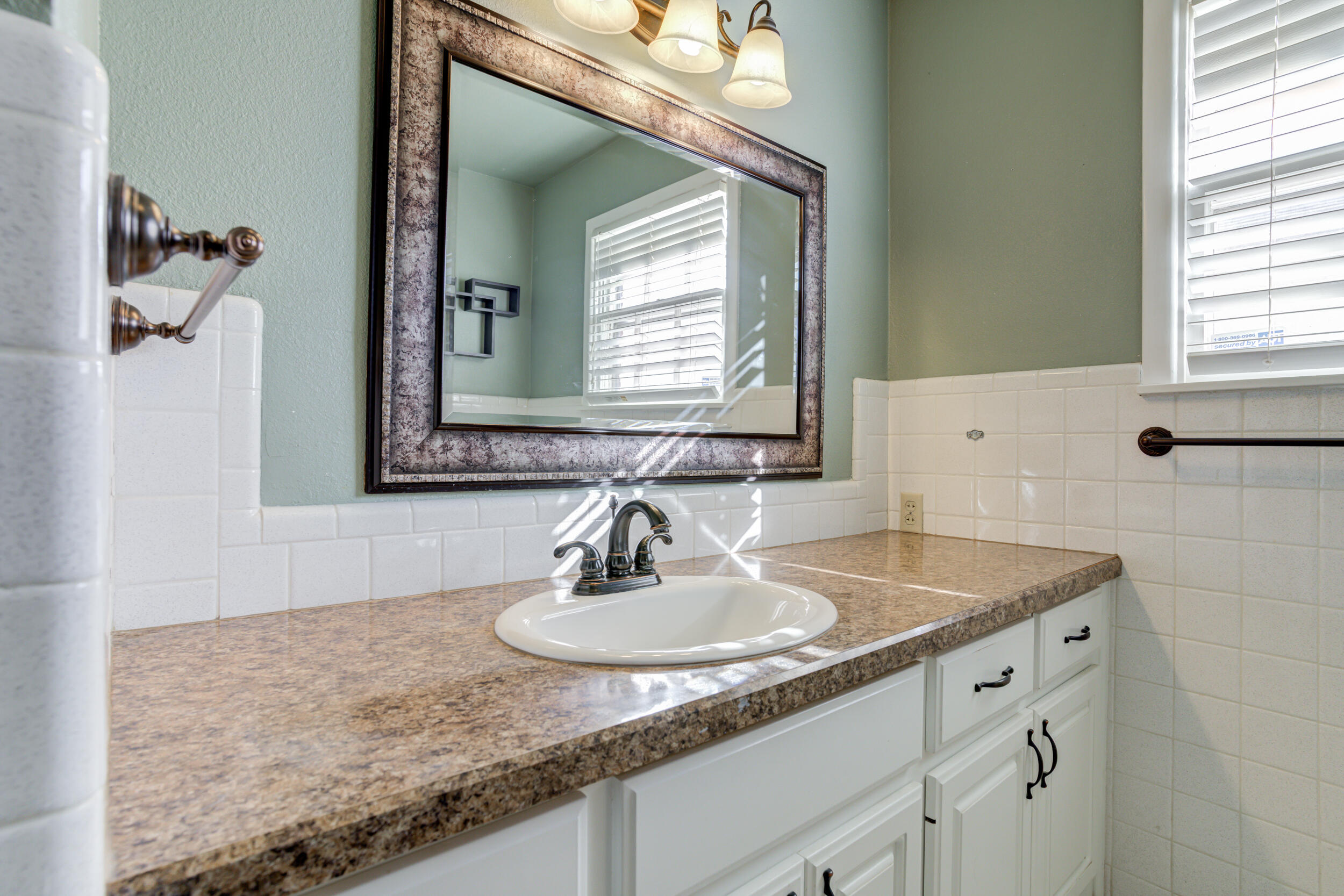 2120 53rd Street Lubbock, TX 79412 - Photo 20 of 32 a bathroom with a granite countertop sink and a mirror