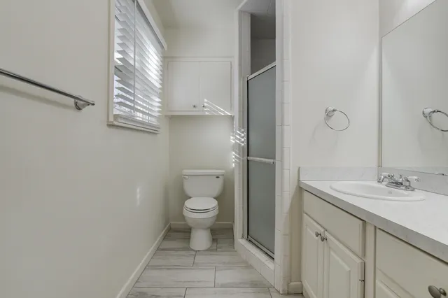 a bathroom with a granite countertop toilet a sink and a mirror