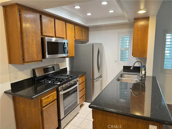 a kitchen with stainless steel appliances granite countertop a stove a refrigerator a sink a microwave oven with granite countertops and cabinets