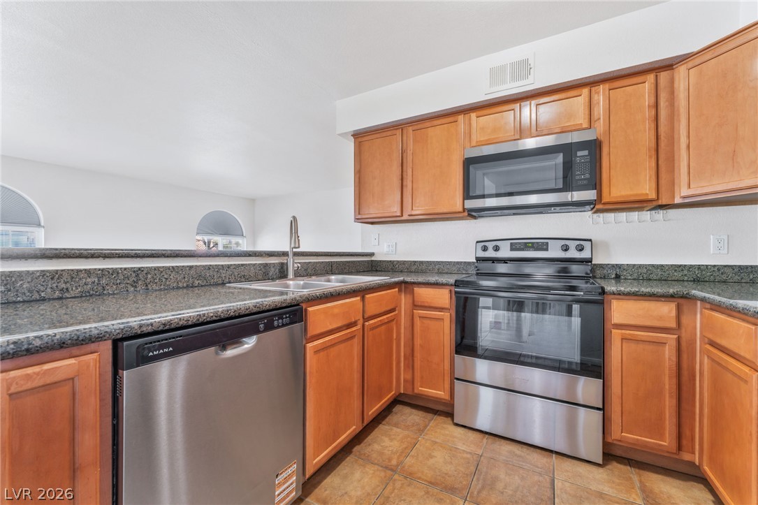 9325 West Desert Inn Road, Unit 177 Las Vegas, NV 89117 - Photo 9 of 24 Rich wood cabinetry paired with dark granite countertops defines this functional kitchen space.