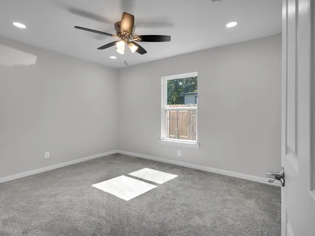 en empty room with windows and ceiling fan