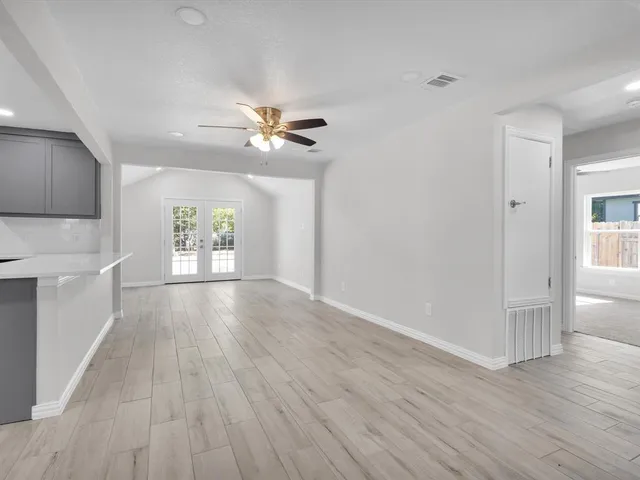 a view of an empty room with a window and wooden floor