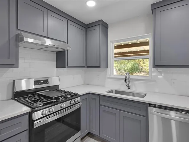 a kitchen with stainless steel appliances a sink a stove and cabinets