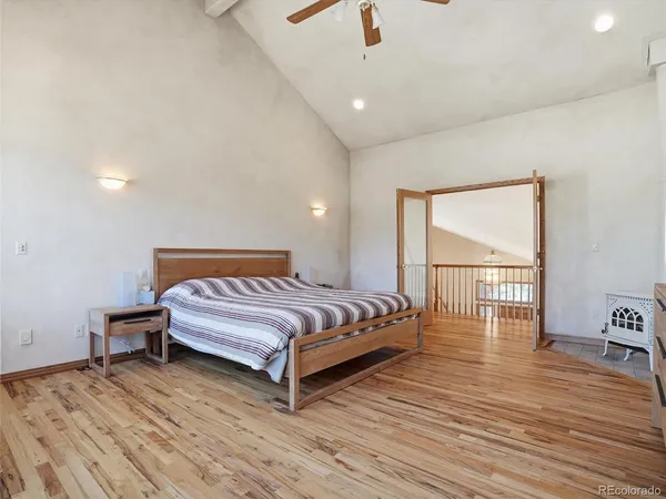 a spacious bedroom with a bed and wooden floor