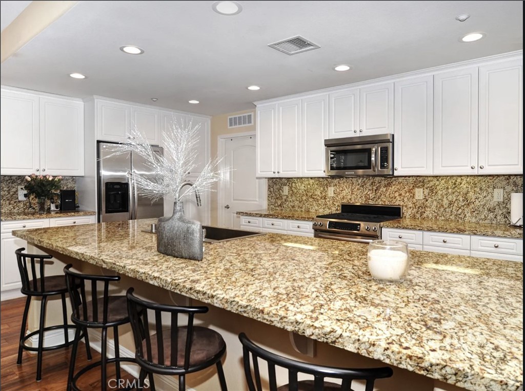 135 Pathway Irvine, CA 92618 - Photo 3 of 12 a kitchen with kitchen island granite countertop a table chairs microwave and cabinets