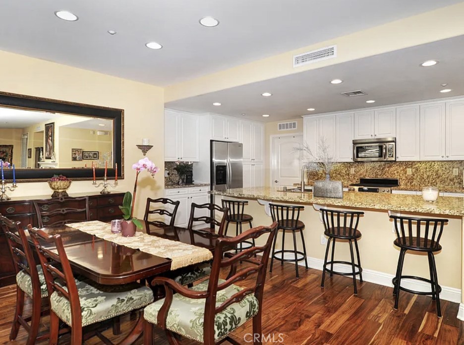 135 Pathway Irvine, CA 92618 - Photo 5 of 12 a kitchen with stainless steel appliances kitchen island granite countertop a dining table chairs and a refrigerator