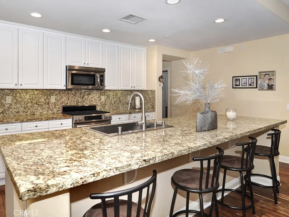 135 Pathway Irvine, CA 92618 - Photo 8 of 12 a kitchen with stainless steel appliances granite countertop a stove a sink a microwave a dining table and chairs