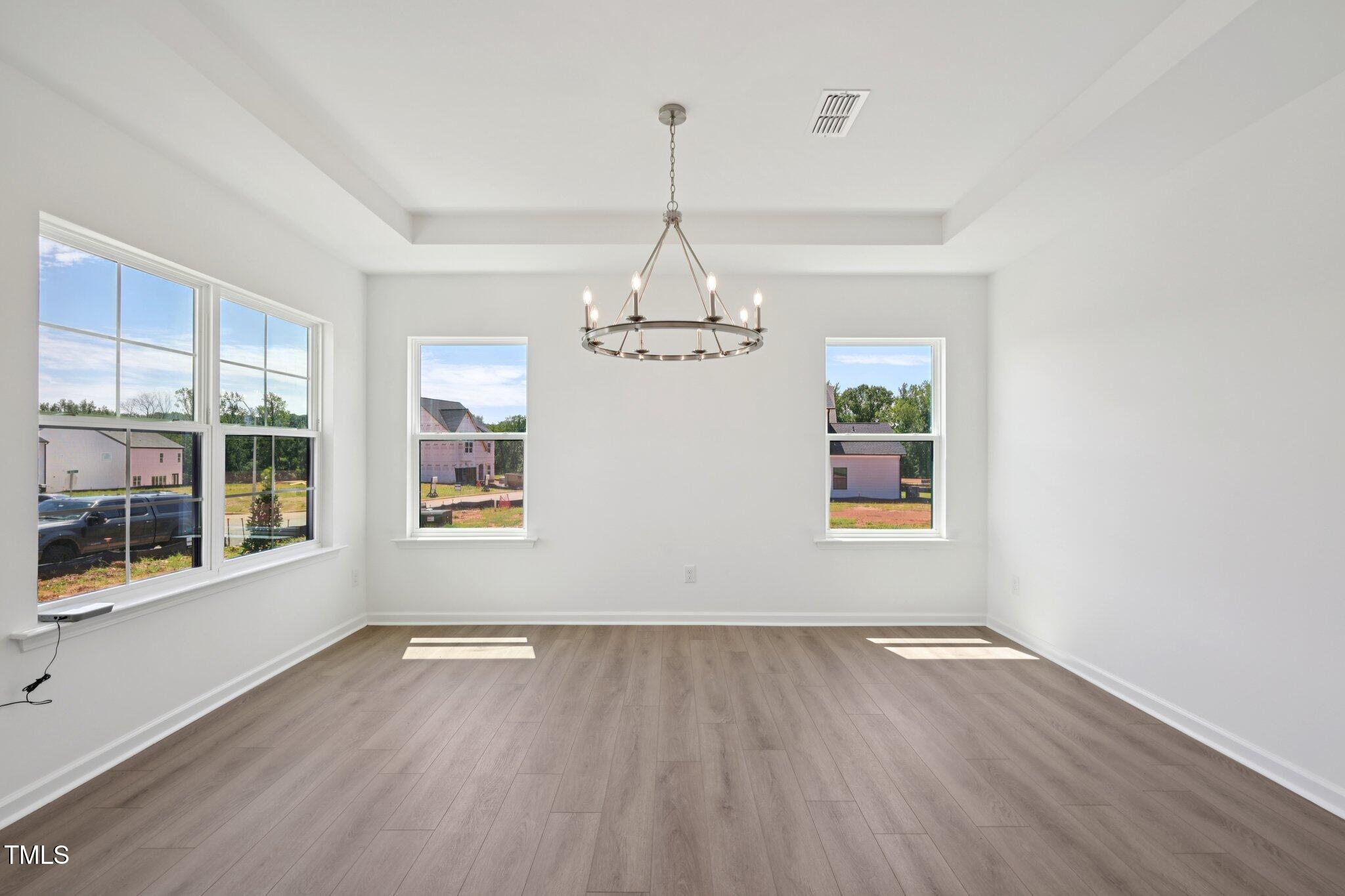 1609 Malcus Court, Unit 67 Fuquay-Varina, NC 27526 - Photo 12 of 40 an empty room with wooden floor chandelier and windows