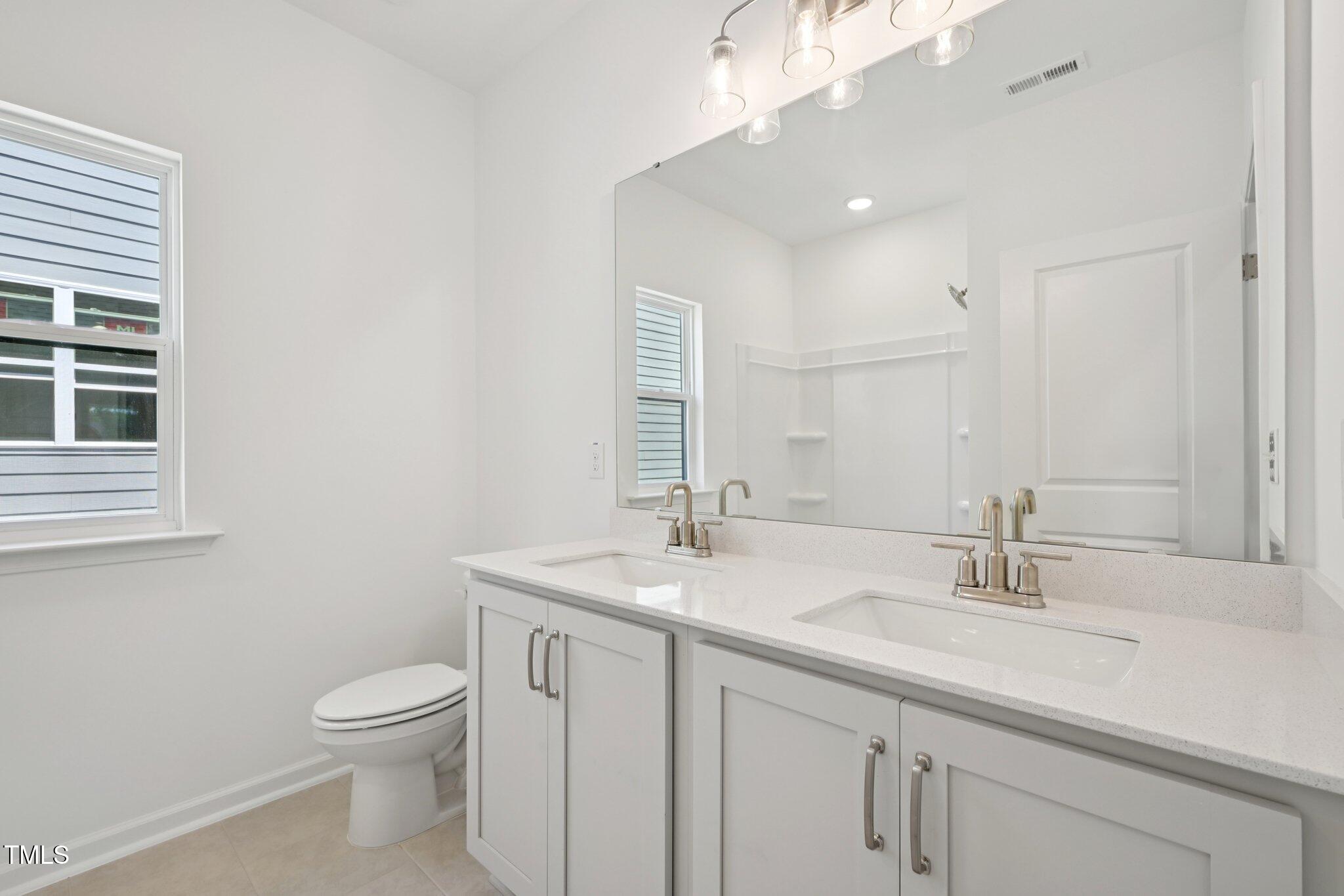 1609 Malcus Court, Unit 67 Fuquay-Varina, NC 27526 - Photo 31 of 40 a bathroom with a granite countertop sink a toilet and a mirror