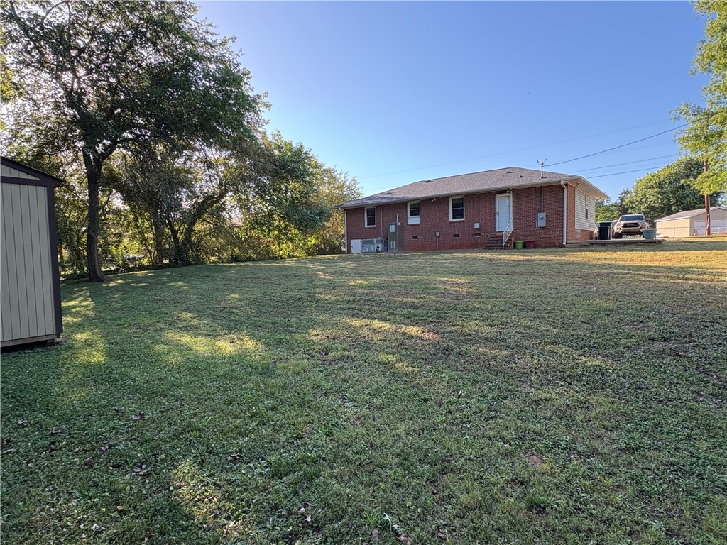 103 Elm Avenue Anderson, SC 29625 - Photo 5 of 19 Expansive green lawn surrounds a classic brick home with ample outdoor space.