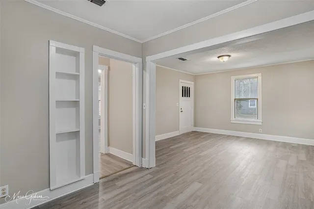 an empty room with wooden floor & windows