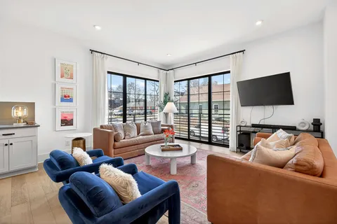 a living room with furniture a flat screen tv and a large window