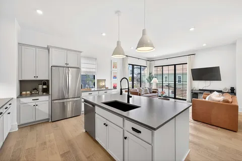 a kitchen with stainless steel appliances granite countertop a refrigerator a stove and a sink with wooden floor