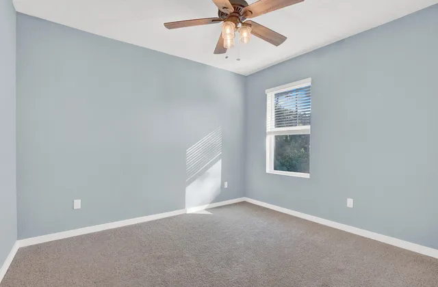 an empty room with a window and a fan