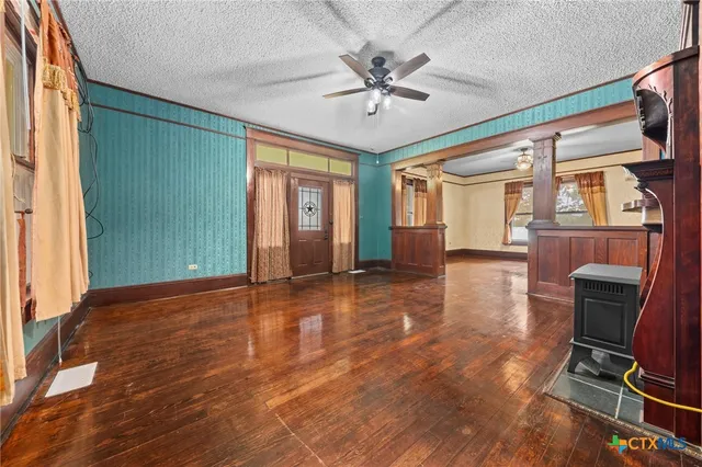 a view of an empty room with a window and wooden floor