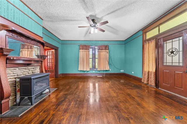 a view of an empty room with a window and wooden floor