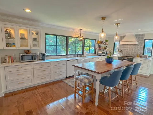 a kitchen with stainless steel appliances granite countertop a stove a sink a dining table and chairs with wooden floor