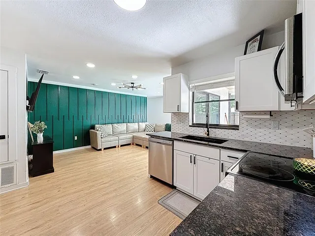 a large white kitchen with kitchen island a stove a sink dishwasher and cabinets with wooden floor