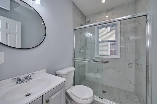 a bathroom with a sink a mirror a toilet and shower