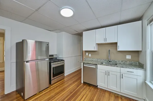 a kitchen with a sink wooden floor and stainless steel appliances
