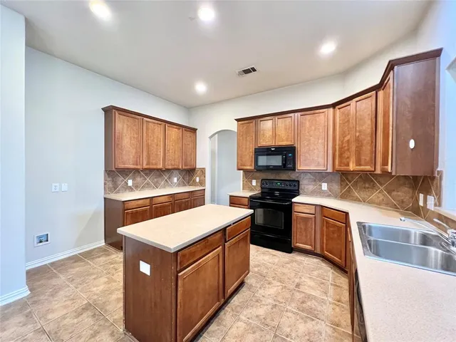 a kitchen with stainless steel appliances granite countertop a stove top oven a sink dishwasher a refrigerator and a oven with wooden floor