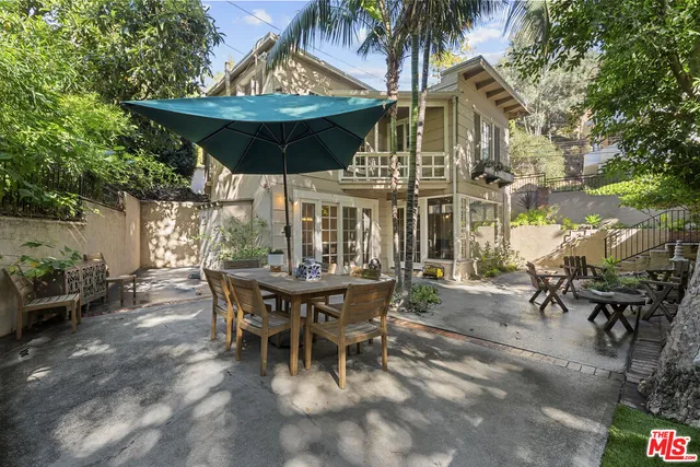 a view of a patio with table and chairs under an umbrella with potted plants
