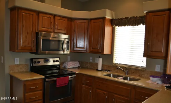 a kitchen with a sink a stove cabinets and a window