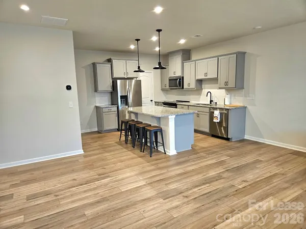 a kitchen with stainless steel appliances granite countertop a stove top oven a sink dishwasher and a refrigerator with wooden floor