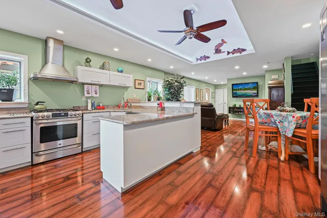 a kitchen with stainless steel appliances kitchen island granite countertop a sink cabinets and wooden floor