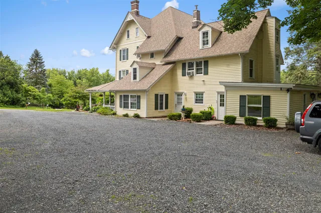 a view of a white house next to a road and trees