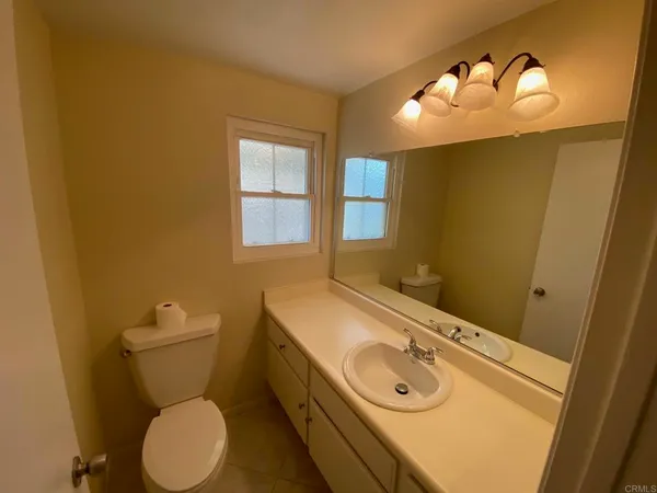 a bathroom with a granite countertop toilet sink and mirror