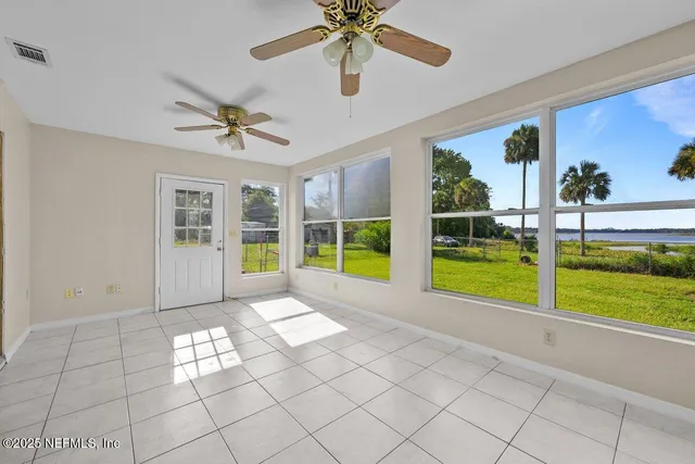 a view of an empty room with a window and ceiling fan
