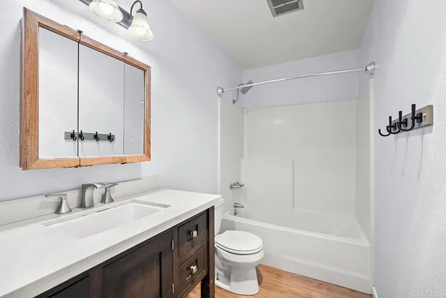 a bathroom with a bathtub shower sink vanity mirror and toilet