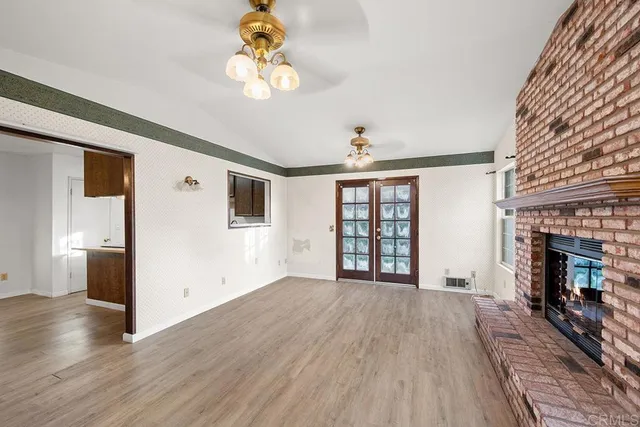 a view of an empty room with wooden floor and a fireplace