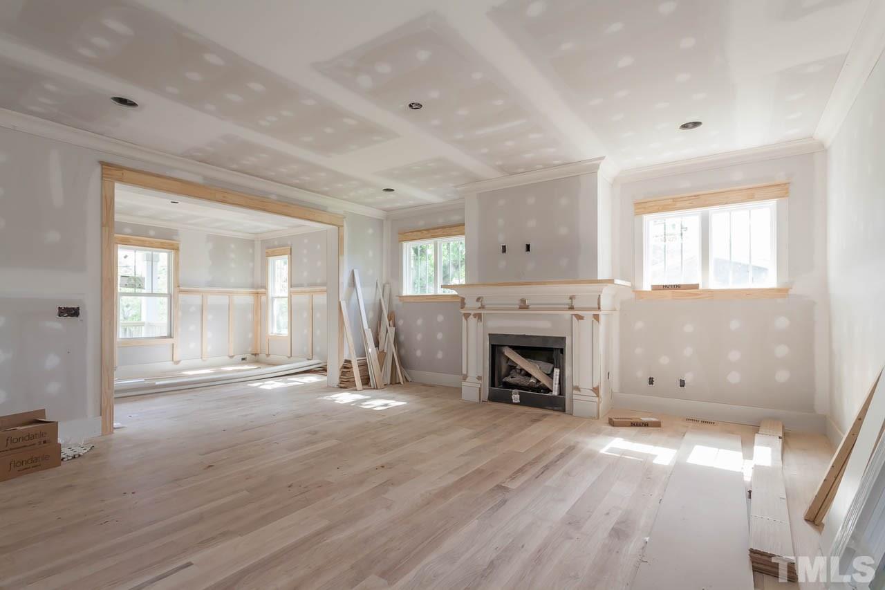 309 Georgetown Road Raleigh, NC 27608 - Photo 2 of 19 an empty room with windows fireplace and wooden floor
